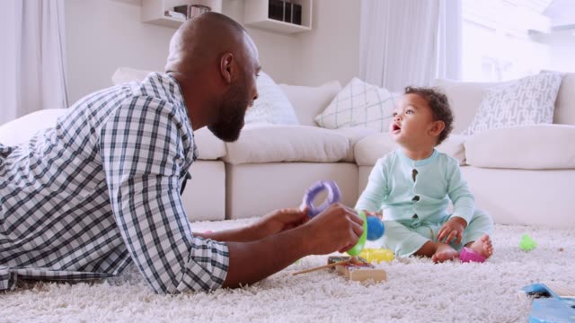 Young-black-father-lying-on-floor-playing-with-his-young-son