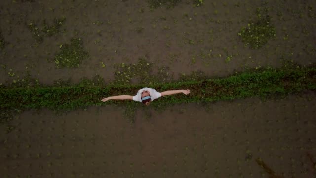 Young-woman-standing-infant-of-rice-terrace-in-Bali-arms-outstretched.-Woman-arms-outstretched-in-nature,-Southeast-Asia.-Drone-Shot