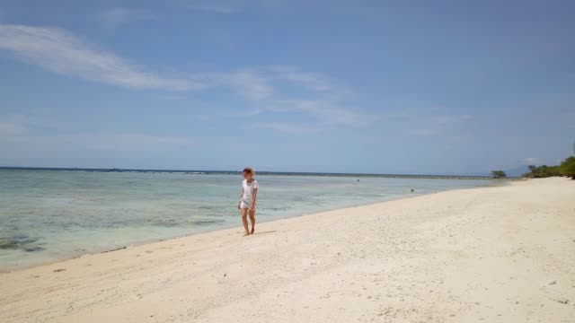 Drone-tiro-joven-teniendo-un-paseo-en-una-playa-tropical-impresionante,-mujer-disfrutando-de-sus-vacaciones-en-la-playa-en-Indonesia,-Drone-tiro-aéreo