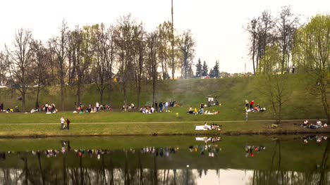 eine-Menge-Leute-auf-ein-frühlingspicknick-am-Ufer-des-Teiches-Stadt