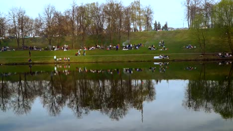 a-lot-of-people-on-a-spring-picnic-on-the-shore-of-the-city-pond,-time-lapse