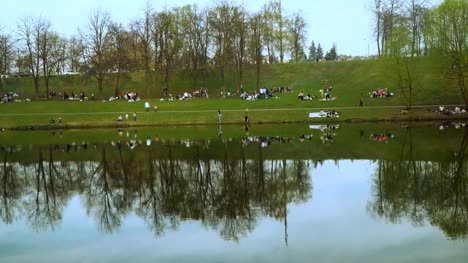 eine-Menge-Leute-auf-ein-frühlingspicknick-am-Ufer-des-Teiches-Stadt,-Zeitraffer