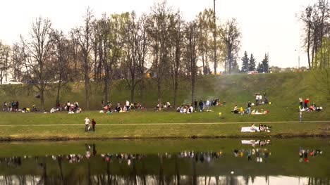 a-lot-of-people-on-a-spring-picnic-on-the-shore-of-the-city-pond,