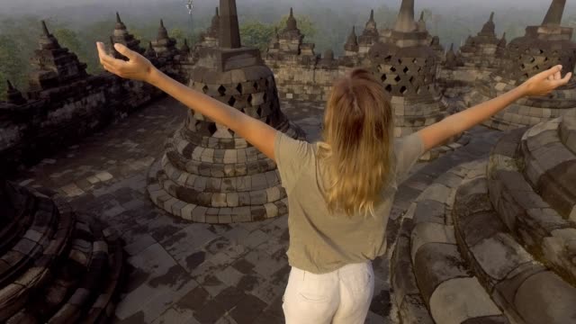 4K-resolution-video-of-travel-girl-embracing-sunrise-at-Borobudur-temple,-Indonesia-.-People-discovery-Asia-concept