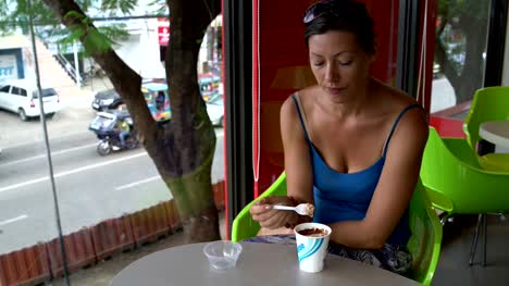 A-woman-in-a-cafe-eating-an-ice-cream-from-a-disposable-cup