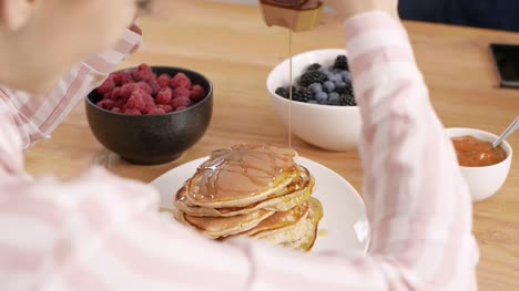 Part-of-woman-eating-pancake-at-kitchen