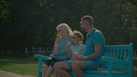 Multi-generation-family-eating-ice-creams-on-bench