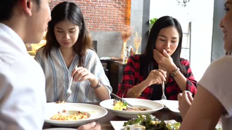 Group-of-Four-young-Asian-people,-one-man,-three-women,-eating-and-talking-at-cafe-and-restaurant.-Friendship-concept
