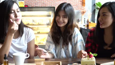 Grupo-de-amigos-de-tres-mujer-asiática-disfrutando-de-un-pastel-de-fresa-y-tener-una-conversación-en-la-cafetería-y-restaurante