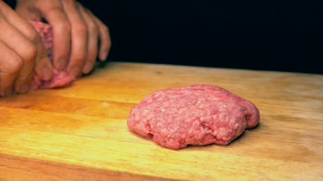 slow-motion-tattooed-chef-hands-forming-hamburger-patties-on-wood-butcher-block