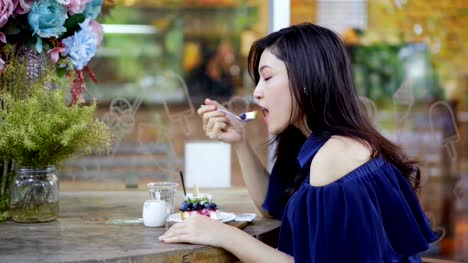 mujer-comiendo-pastel-de-queso-de-arándanos-en-café