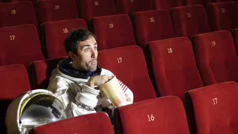 Ein-Film-Astronaut-schaut-einen-Film-und-essen-Popcorn-und-genießen-den-Film.-Konzept:-Raum-und-Kino-Filme,-Film-der-anderen-Welt,-surrealen-Situationen.