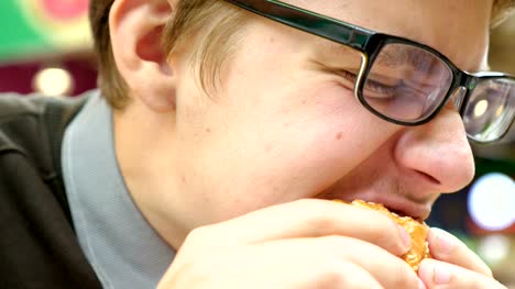 Un-joven-está-comiendo-una-hamburguesa-en-un-centro-comercial.