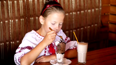 happy-smiling-teen-girl,-child-eats-ice-cream-in-a-cafe.-she-is-dressed-in-Ukrainian-national-clothes,-embroidery,-vishivanka