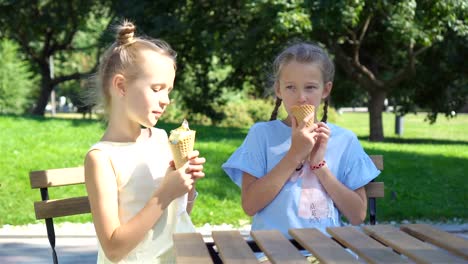 Kleine-Mädchen-essen-Eis-im-Freien-während-des-Sommers-im-Café-im-freien