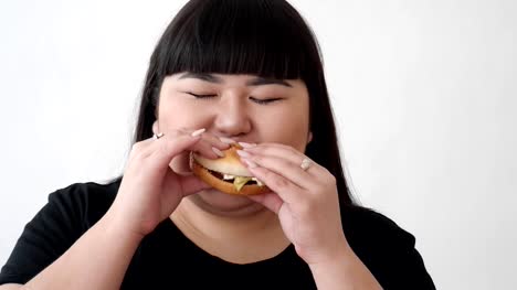 Das-Mädchen-des-asiatischen-Aussehens-einen-Burger-isst-und-genießt-den-Geschmack.-keine-gesunde-Ernährung-für-Jugendliche