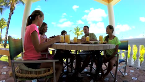 Caucasian-family-dining-on-vacation-beach-hotel-decking