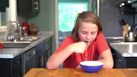 Un-niño-comiendo-un-plato-de-mac-y-el-queso-en-casa-en-una-cocina.