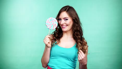 Woman-smiling-girl-with-lollipop-candy-on-green-4K