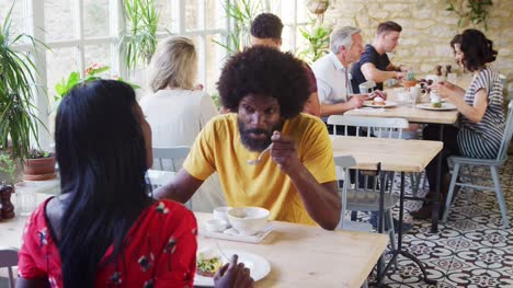 Black-adult-couple-talking-over-brunch-in-a-busy-restaurant,-close-up