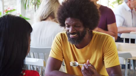 Middle-aged-black-man-eating-breakfast-and-talking-with-his-girlfriend-at-a-restaurant,-her-back-to-the-camera