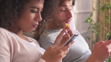 Couple-using-mobile-phone-during-breakfast-on-bed