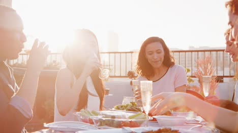 Friends-Gathered-On-Rooftop-Terrace-For-Meal-With-City-Skyline-In-Background