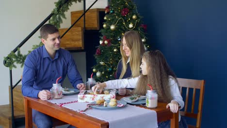 Familia-feliz-comiendo-galletas-de-Navidad-en-vísperas-de-Navidad