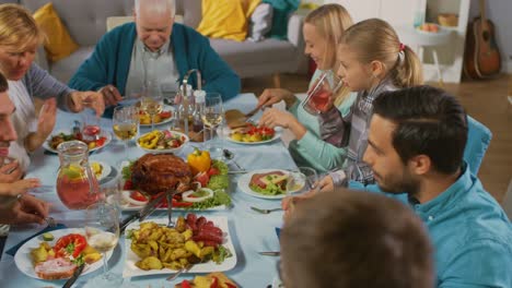 Große-Familie-und-Freunde-feiern-zu-Hause-versammelt-vielfältige-Gruppe-von-jungen-und-alten-Menschen-am-Tisch.-Essen,-Essen,-trinken-und-Spaß-Gespräch.-Tagsüber-fest.