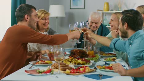 Big-Family-and-Friends-Celebration-at-Home,-Diverse-Group-of-Children,-Young-Adults-and-Old-People-Gathered-at-the-Table-have-Fun-Conversation.-Clinking-Glasses-and-Making-Toast.-In-Slow-Motion.