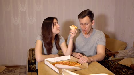 Brünette-Frau-und-Mann-zu-Hause-Pizza-essen