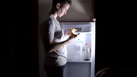 junger-Mann-hat-eine-Banane-in-den-Kühlschrank-in-der-Nacht