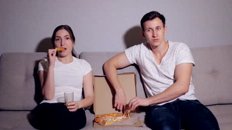 Das-glückliche-Paar-eine-Pizza-essen-und-einen-Film-ansehen-auf-dem-sofa
