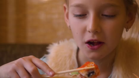 Junger-Teenager-Mädchen-essen-Sushi-Rolle-mit-Stäbchen-in-japanischen-Café-hautnah