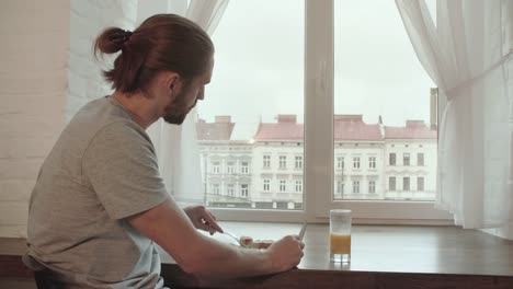 Young-Man-Drinking-Juice-And-Having-Breakfast-At-Home