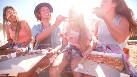 Amigos-Riendo-y-disfrutar-de-una-pizza-en-un-día-de-verano