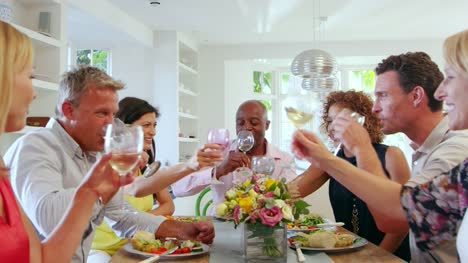 Reife-Freunden-treffen-um-den-Tisch-im-Dinnerparty-Ball-R3D