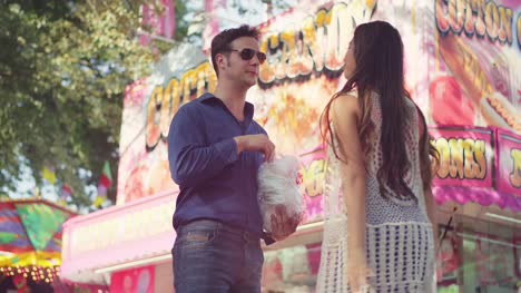 A-couple-eating-cotton-candy-and-sharing-sunglasses-at-a-fair