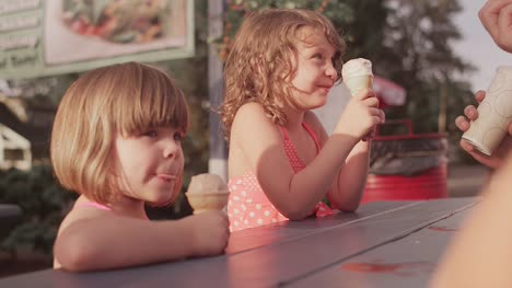 Dos-hermanas-comer-helados-con-su-familia-en-la-mesa-de-día-de-campo