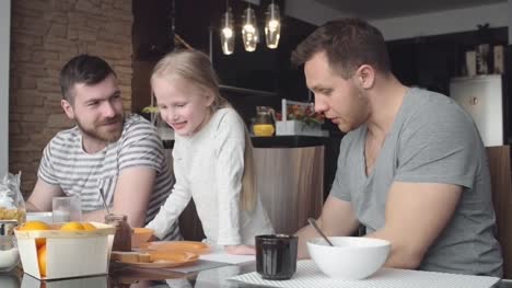 Little-girl-talking-with-same-sex-parents-at-breakfast
