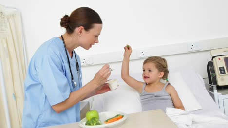 Nurse-feeding-sick-little-girl-in-bed