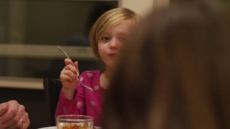 Close-up-on-a-little-girl-eating-dinner-with-her-family