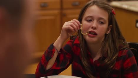 Ein-Mädchen-fallen-eine-Spaghetti-Nudel-in-den-Mund,-beim-Abendessen-mit-ihrer-Familie