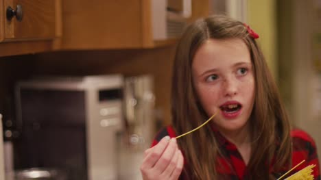 Mädchen-legt-eine-Spaghetti-Nudel-in-einen-Topf-mit-Wasser-und-beißt-es