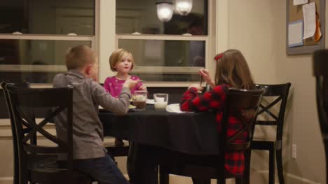 Three-kids-eating-spaghetti-and-meatballs-at-the-dinner-table-together