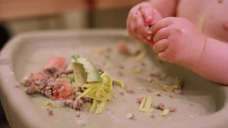Nahaufnahme-eines-Babys-in-einen-Hochstuhl-Sitzerhöhung-chaotisch-Essen-mit-den-Händen