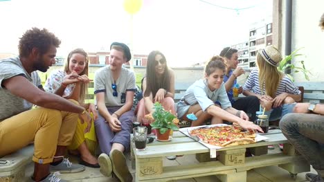 Attractive-young-people-sitting-around-the-table-on-the-rooftop-terrace