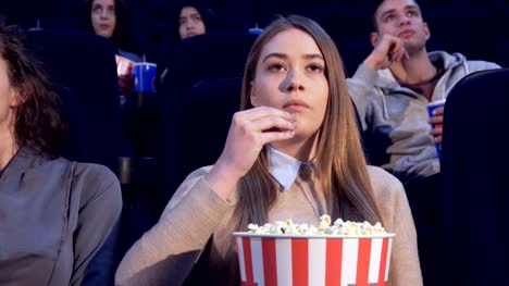 Girl-slowly-puts-the-popcorn-in-her-mouth-at-the-movie-theater