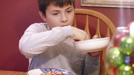 Young-boy-eating-from-a-bowl-of-gingerbread-cookie-decorations