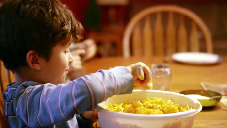 Young-boy-scooping-macaroni-and-cheese-onto-plate-at-dinner-table
